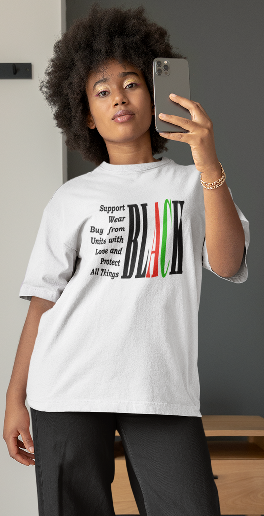 Person taking a mirror selfie wearing a white t-shirt with a graphic design in a bedroom.