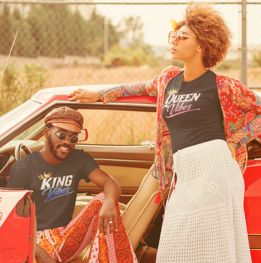Two people standing next to a red car with a scenic background